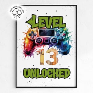 以下が含まれることがあります： カラフルな水彩画風のゲームコントローラーの画像が描かれたフレームプリント。 「LEVEL 13 UNLOCKED」の文字は緑色で表示され、数字の13は通貨で装飾されています。 プリントは白い背景にあります。