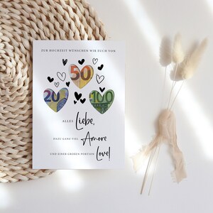 May include: A white card with black hearts and the words "Zur Hochzeit w&uuml;nschen wir euch von" at the top. The hearts are filled with euro bills. The text below the hearts reads "Alles Liebe, Amore Love!" with the words "dazu ganz viel" and "und einer gro&szlig;en Portion" below.