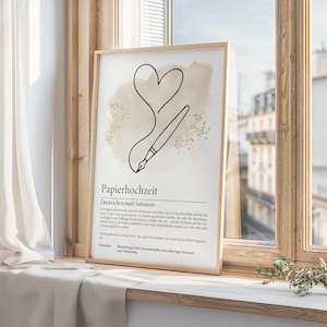 K&ouml;nnte beinhalten: Ein gerahmter Druck mit einer minimalistischen Strichzeichnung eines Herzens und eines Stifts, mit dem deutschen Wort "Papierhochzeit" unten. Das Kunstwerk hat eine neutrale Farbpalette mit beigem Hintergrund und wird auf einer Fensterbank ausgestellt.