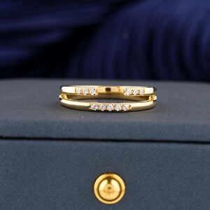Könnte beinhalten: Ein goldener Ring mit einer doppelten Band und kleinen Diamanten, die in der Mitte eingesetzt sind.
