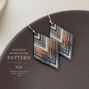 Könnte beinhalten: Ein Paar Perlenohrringe in Diamantform mit einem geometrischen Muster in Blautönen, Weiß, Braun und Kupfer. Die Ohrringe sind in Ziegeltechnik gefertigt und 3,5 cm breit und 5 cm lang. Das Muster umfasst 7 Farben.