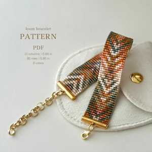 Puede incluir: Un brazalete tejido en telar con un patrón geométrico en tonos de marrón, naranja, blanco y gris. El brazalete mide 5,85 pulgadas de largo y 0,69 pulgadas de ancho, y está hecho con 8 colores de cuentas. El brazalete está unido a una cadena dorada con un cierre.