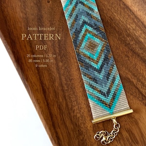 Pode incluir: Um padrão de pulseira de tear PDF com um design geométrico em tons de azul, turquesa, dourado e branco. O padrão é para uma pulseira que mede 1,33 polegadas de largura e 5,85 polegadas de comprimento e utiliza 9 cores.