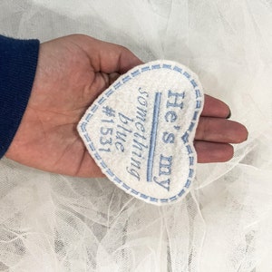 May include: White heart-shaped fabric patch with blue embroidered text that reads "He's my something blue #1531".