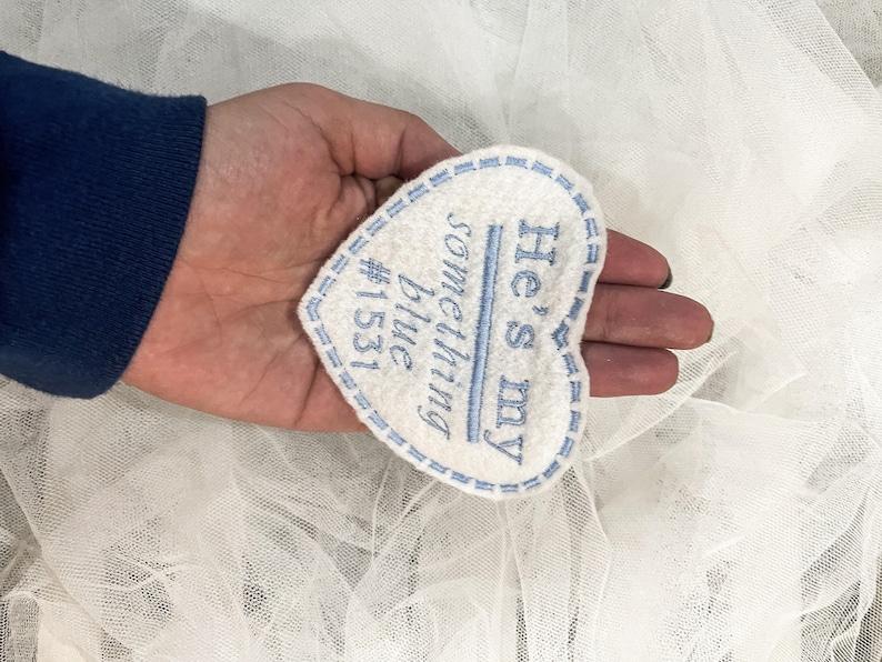 May include: White heart-shaped fabric patch with blue embroidered text that reads "He's my something blue #1531".