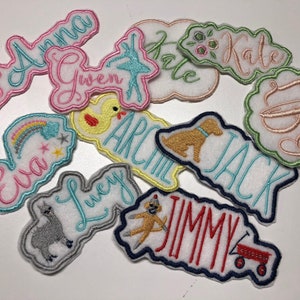 May include: A collection of colorful embroidered iron-on patches with various names, including Anna, Gwen, Kate, Eva, Lucy, Archie, Jack, Jimmy, and a monogram. Each patch features a unique design, such as a unicorn, a rainbow, a duck, a ballerina, a dog, a llama, and a monkey.