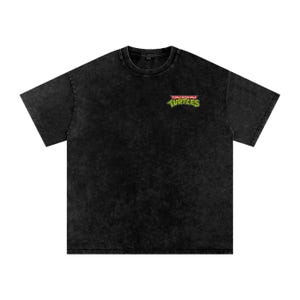 Könnte beinhalten: Schwarzes, übergroßes T-Shirt mit verwaschener, strukturierter Optik. Das Shirt zeigt ein kleines, farbenfrohes Teenage Mutant Ninja Turtles-Logo auf der oberen linken Brust. Das Logo enthält die Wörter "Teenage Mutant Ninja Turtles" und das Wort "Turtles" in Grün.