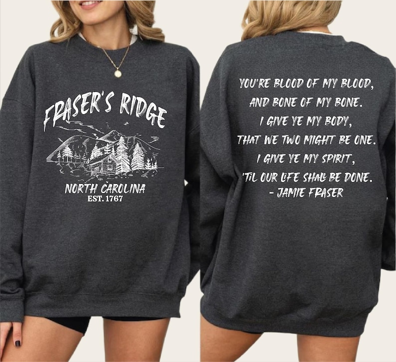 a gray sweatshirt with text and graphics printed on it. The text on the back of the sweatshirt reads: "You're blood of my blood, and bone of my bone. I give ye my body, that we two might be one. I give ye my spirit, 'till our life shall be done." The sweatshirt also has a graphic of a mountain landscape.