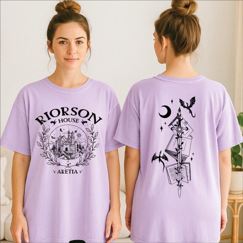 A woman wearing a purple t-shirt with a graphic design on the front and a back featuring a black and white illustration of a castle, a crescent moon, and a dragon.
