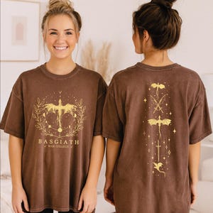 Two women wearing brown t-shirts with a dragon design and text on the front and back.