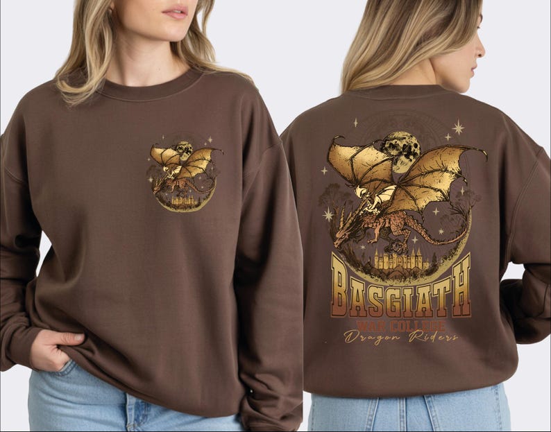 a woman wearing a brown sweater with a graphic design featuring a dragon and a castle. The design includes the text "BASGLATH WAR COLLEGE Dragon Riders" on the back of the sweater.