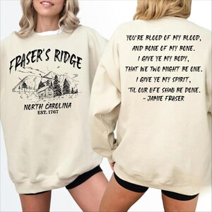 a woman wearing a white sweatshirt with text and graphics printed on it.