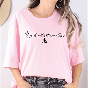 a woman wearing a pink shirt with a bird on it