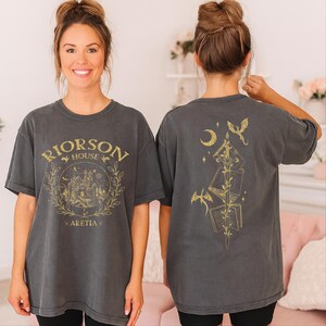 A woman wearing a gray t-shirt with a graphic design on the front and a back featuring a similar design.