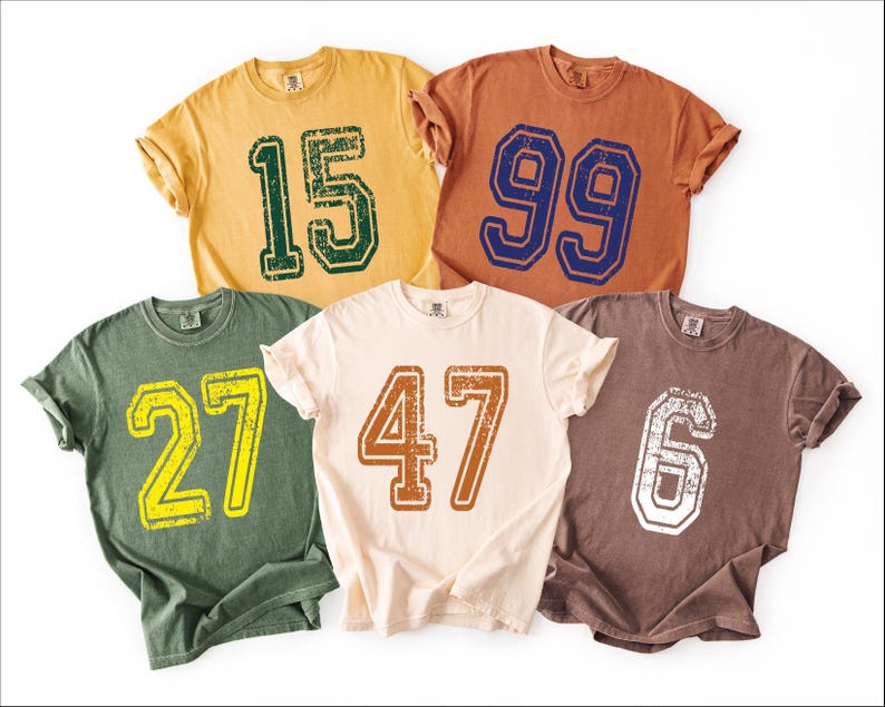 a collection of five t-shirts, each with a different number printed on it.