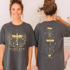 A woman wearing a grey t-shirt with a graphic design and text on the front and back.