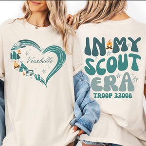 two women wearing white t-shirts with text and graphics printed on them.