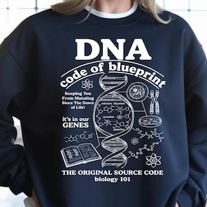 May include: A dark navy blue crewneck sweatshirt featuring a white graphic print of a DNA double helix, chemical structures, and scientific illustrations. The text reads DNA code of blueprint, Keeping You From Mutating Since The Dawn of Life, it's in our GENES, THE ORIGINAL SOURCE CODE, and biology 101.