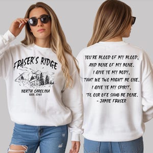 A woman wearing a white sweatshirt with text and graphics printed on it.