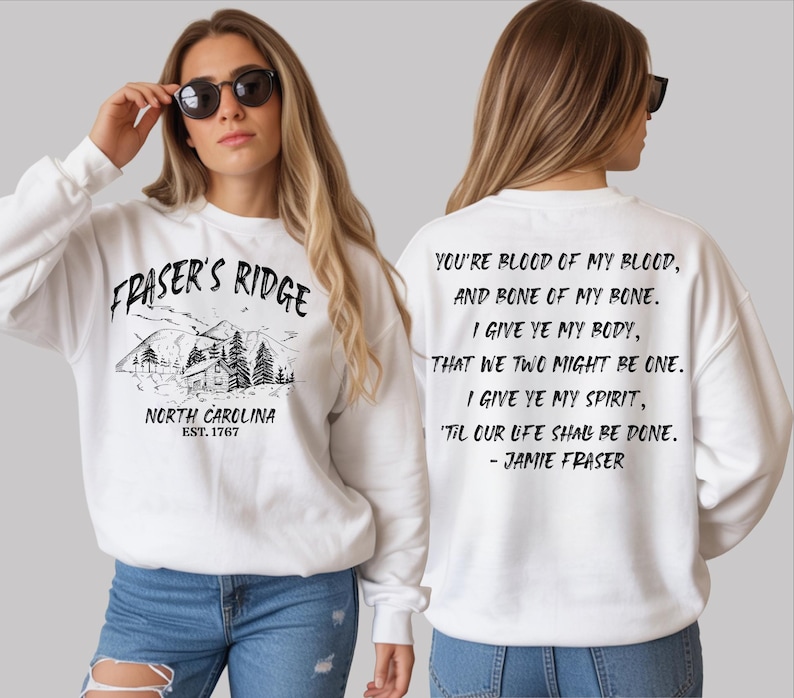 A woman wearing a white sweatshirt with text and graphics printed on it.
