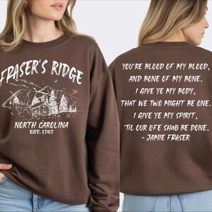 a woman wearing a brown sweatshirt with text and graphics printed on it.