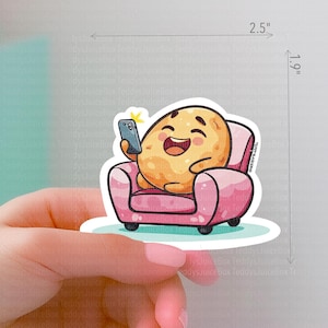 May include: A cartoon potato character wearing a pink armchair and holding a smartphone. The potato has a happy expression and is sitting in a pink armchair. The sticker is 2.5 inches wide and 1.9 inches tall.