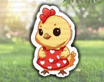 May include: A yellow chick wearing a red dress with white hearts. The chick has a red comb and black eyes.