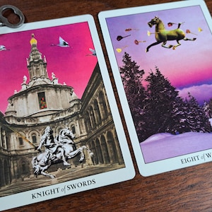 Puede incluir: Dos cartas de tarot, Caballero de Espadas y Ocho de Bastos, sobre una superficie de madera. La carta del Caballero de Espadas presenta un caballero a caballo cabalgando por un patio con un cielo rosa. La carta del Ocho de Bastos muestra ocho bastos volando por el aire sobre un paisaje nevado con un cielo morado.