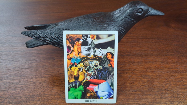 Puede incluir: Una carta de tarot con el n&uacute;mero XV y las palabras "THE DEVIL" impresas en la parte inferior. La carta presenta un collage de im&aacute;genes, que incluyen la cara de una mujer, el cuerpo de una mujer, la mano de un hombre y un par de dados.