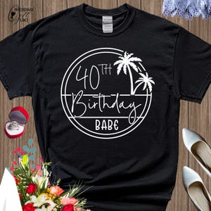 Può includere: Maglietta nera con una grafica circolare bianca che dice "40th Birthday Babe" con palme all'interno del cerchio.