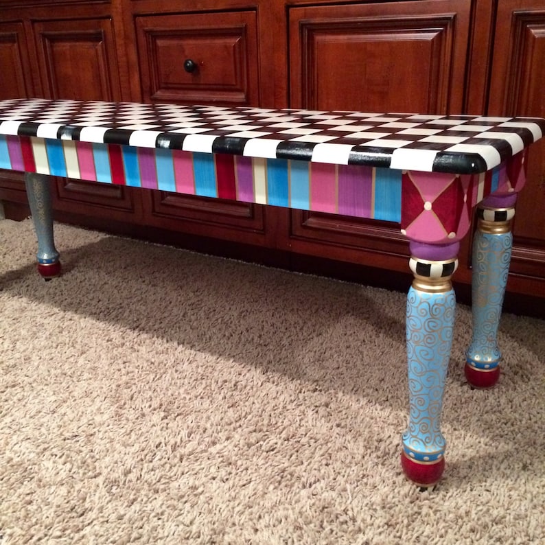 May include: A colourful painted bench with a black and white chequered top, a multi-coloured stripe design on the front, and gold and blue painted legs with decorative swirls.