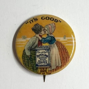 May include: A vintage button featuring a couple kissing in front of a can of "Dutch Java and Santos Blend" coffee. The button is yellow with a white border and the text "It's Good" in black.