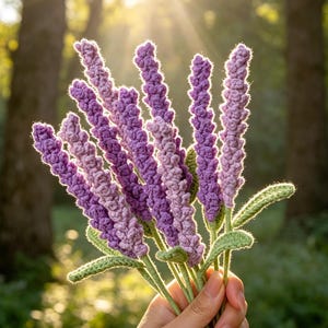 Könnte beinhalten: Ein Strauß aus gehäkelten Lavendelstielen mit texturierten violetten Blütenähren und hellgrünen gehäkelten Blättern. Die Stiele sind zusammengebunden und zeigen eine komplexe Garnarbeit mit verschiedenen Violetttönen und weichem grünem Blattwerk.
