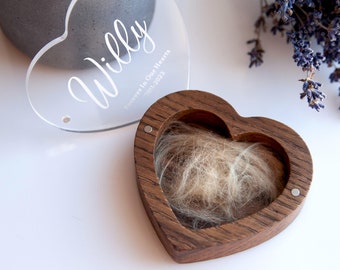 May include: A wooden heart-shaped box with a clear acrylic lid. The lid has the inscription "Willy Forever in Our Hearts 2011-2023". The box is filled with light brown fur.