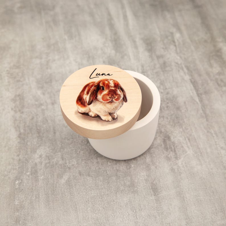 A wooden lid with a picture of a rabbit on it, placed on a white ceramic container.