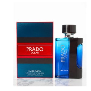 Op de afbeelding: Een parfumfles en doos set. De fles is blauw en zwart met de tekst "PRADO OCEAN". De doos is blauw en rood met dezelfde tekst. De fles bevat 100 ml parfum.