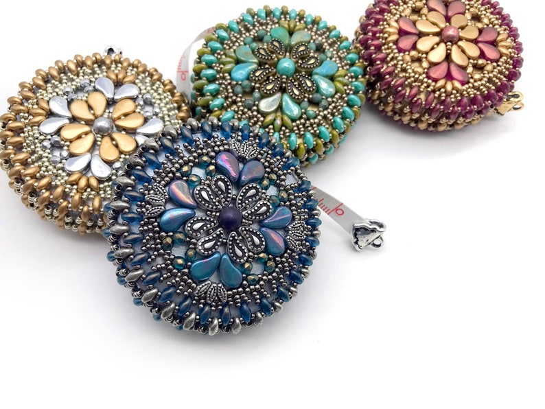 May include: Four beaded measuring tapes with different colored beads and designs. The tapes are in shades of gold, teal, purple, and blue.