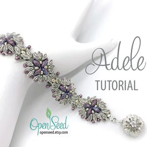 May include: A silver and purple beaded bracelet with a flower design. The bracelet is on a white surface and has a silver charm attached to the end. The text "Adele TUTORIAL" is visible in the image.