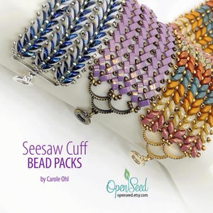 May include: Close-up of three beaded cuff bracelets in shades of blue, purple, and a mix of orange, yellow, and pink. The bracelets have intricate beadwork and decorative clasps. The text "Seesaw Cuff BEAD PACKS" is visible.