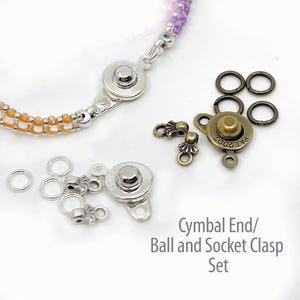 May include: A close-up of jewelry-making supplies, including silver and bronze-toned ball and socket clasps, jump rings, and cymbal end findings. The image also shows a beaded bracelet with orange and purple beads. Text reads: Cymbal End/ Ball and Socket Clasp Set.