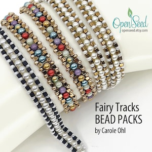 May include: Close-up of several beaded bracelets in various colors, including black, white, gold, and multicolored beads. The bracelets are arranged on a white surface. Text on the image reads "Fairy Tracks BEAD PACKS by Carole Ohl."