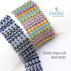 May include: Two beaded bracelets, one with a colorful striped pattern and the other with a blue, silver, and white pattern. The bracelets are called "Hubble Stripes Cuff Bead Packs".