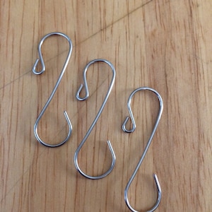 May include: Three silver S-shaped hooks, commonly used for hanging ornaments or other decorative items.