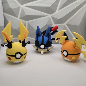 May include: Three cartoon character figurines. One is yellow with black accents and yellow lightning bolt-shaped ears. Another is blue and black with white spikes. The third is orange with yellow lightning bolt-shaped ears.