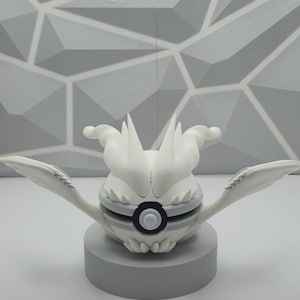 May include: A white spherical figure with pointed, wing-like appendages extending from the sides and a central circular black and white button detail. The object features sharp, flame-like protrusions on top and rests on a solid gray cylindrical base.
