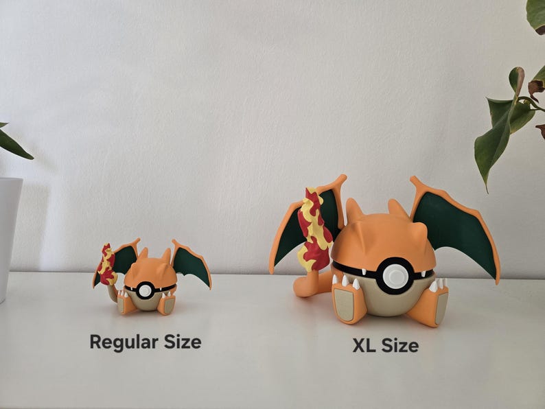 May include: Two orange and tan dragon-like figurines with dark green wings and a flame-tipped tail. The smaller figure is labeled Regular Size and the larger figure is labeled XL Size. Both figures feature a central white and black circular emblem.