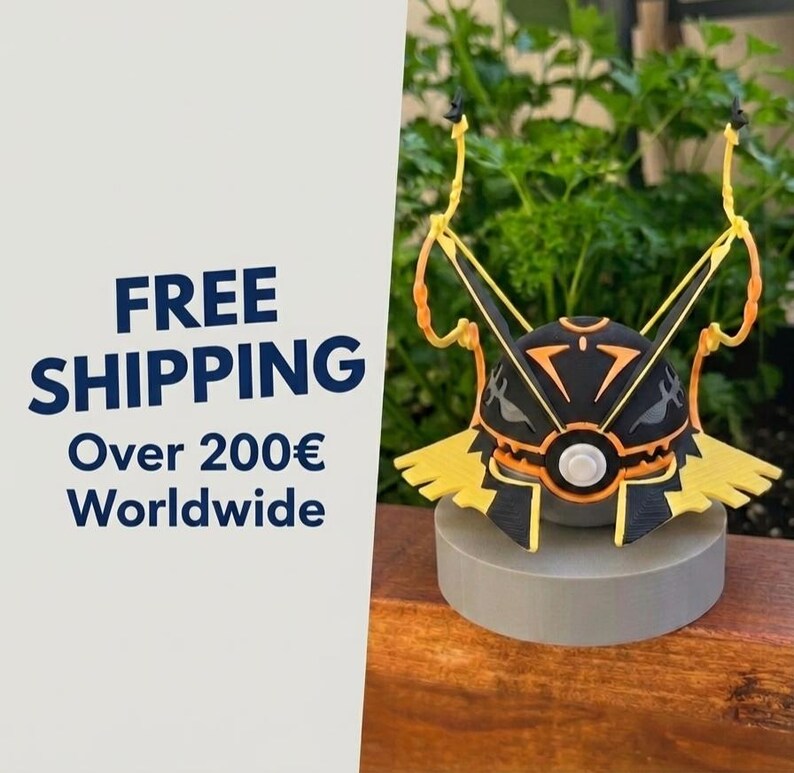May include: A spherical figurine featuring a black and orange geometric pattern with a central white circular element, two tall yellow antennae-like structures extending upwards, and a yellow base, all mounted on a solid gray cylindrical stand.