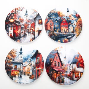 Op de afbeelding: Set van vier ronde onderzetters met aquarel schilderijen van Europese stadstaferelen. Elke onderzetter toont een ander beeld van schilderachtige straten met kleurrijke gebouwen, straatlantaarns en herfstbladeren. De onderzetters beschermen oppervlakken.