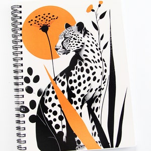 Puede incluir: Una ilustración en blanco y negro de un guepardo con follaje naranja y negro sobre un fondo blanco. El guepardo está sentado con la cabeza girada hacia la izquierda. El fondo tiene un gran círculo naranja.