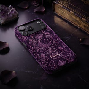 May include: A purple smartphone case featuring a dark floral damask pattern with rose motifs, a crescent moon, stars, and two crowns. The word Valinty is printed in a light script font near the bottom of the case, which has a black camera module.